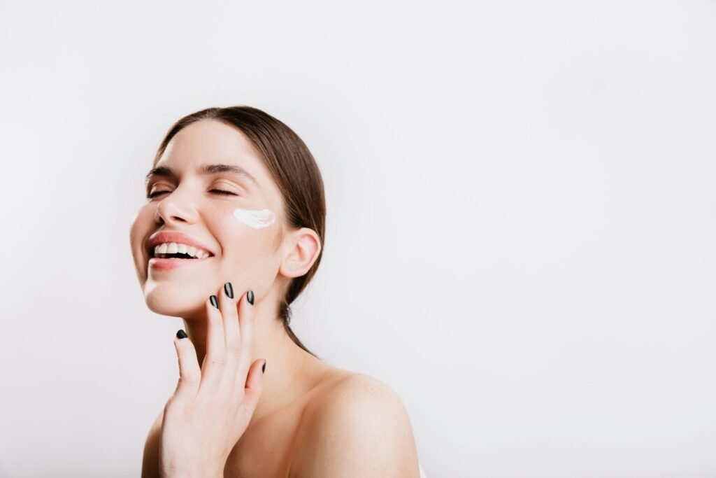 Smiling woman touching her glowing skin against a light background