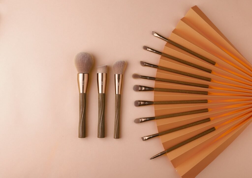 Makeup brushes laid out on a soft blush background